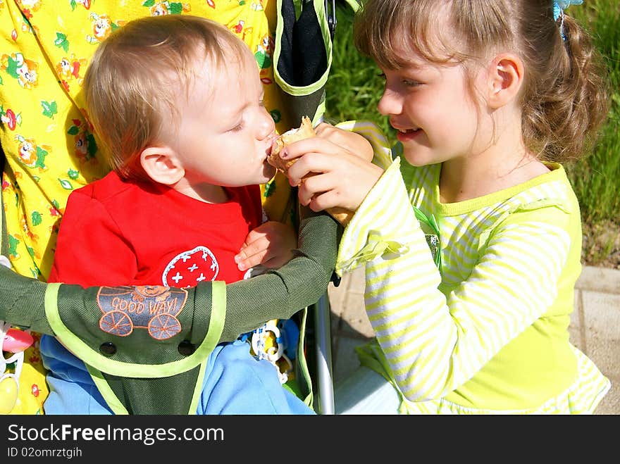 The girl sits about the boy and feeds with its ice-cream in the summer. The girl sits about the boy and feeds with its ice-cream in the summer