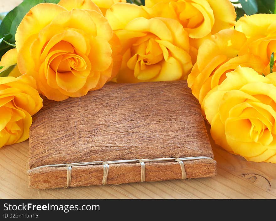 Bouquet of yellow roses on a book with a textured handmade cover