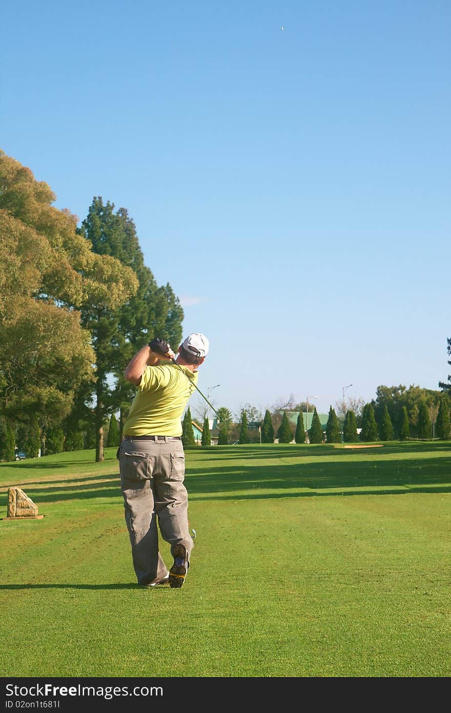 Young male golfer hitting the ball from the fairway on a beautiful summer day. Young male golfer hitting the ball from the fairway on a beautiful summer day