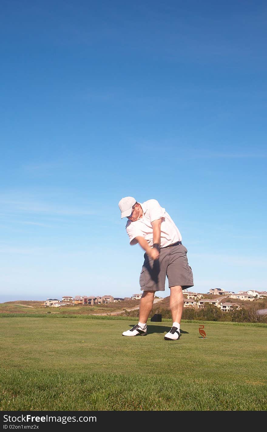 Young male golfer hitting the ball from the tee box next to the ocean on a beautiful summer day. Young male golfer hitting the ball from the tee box next to the ocean on a beautiful summer day