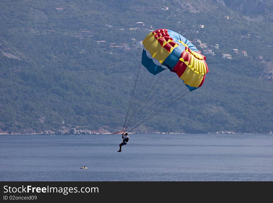 A man flying on a parachute over the bay near the town of Budva, Montenegro. A man flying on a parachute over the bay near the town of Budva, Montenegro