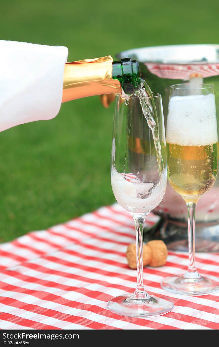 Champagne being poured to glasses at a summer picnic. Champagne being poured to glasses at a summer picnic