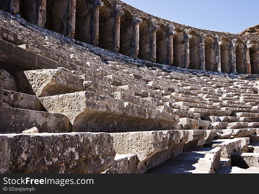 Stone benches and part of stone gallery in ruins of an ancient amphitheater in the disappeared city Aspendos, Turkey