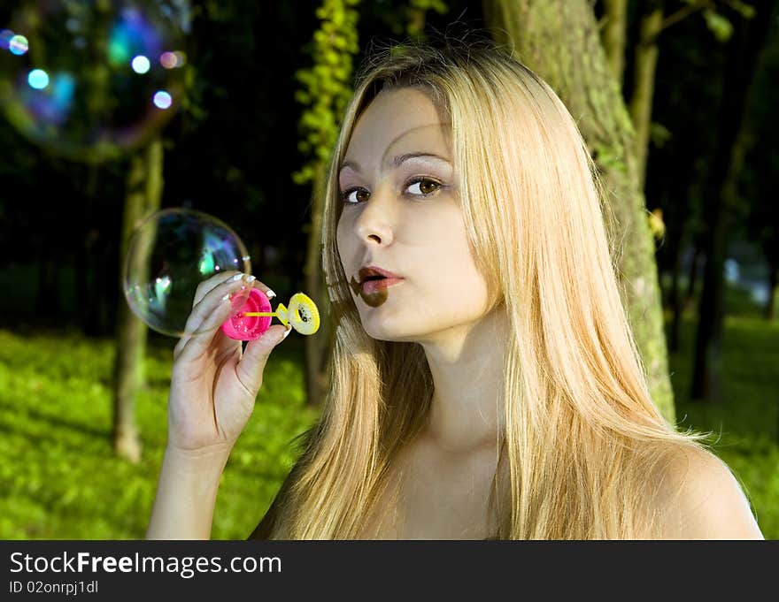 Blonde young woman blowing soap bubbles in summer day. Blonde young woman blowing soap bubbles in summer day