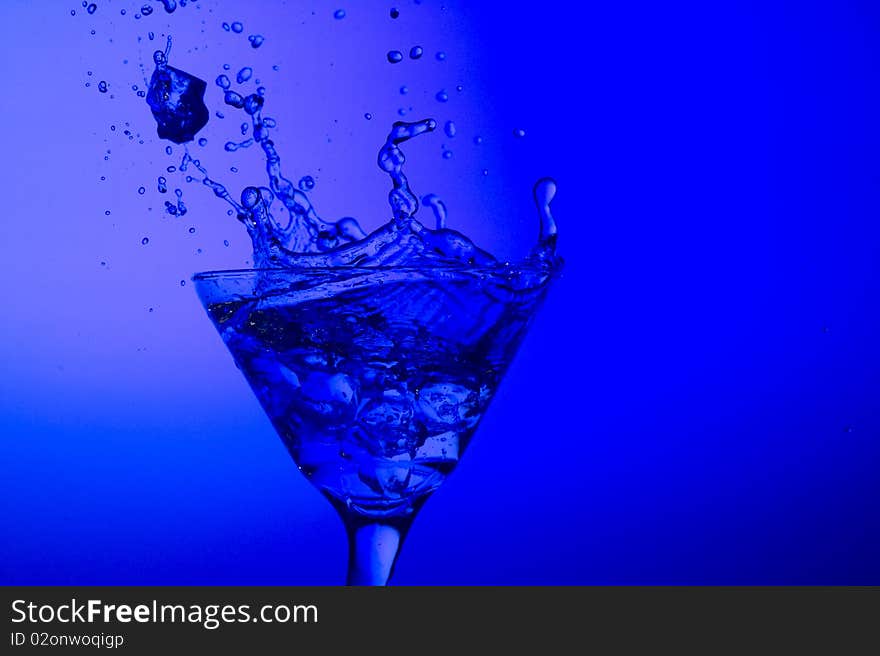 Splashing cocktail on the blue background