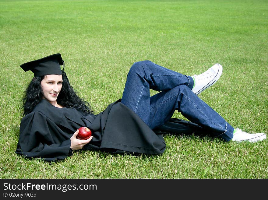 Young caucasian student laying on the grass with apple