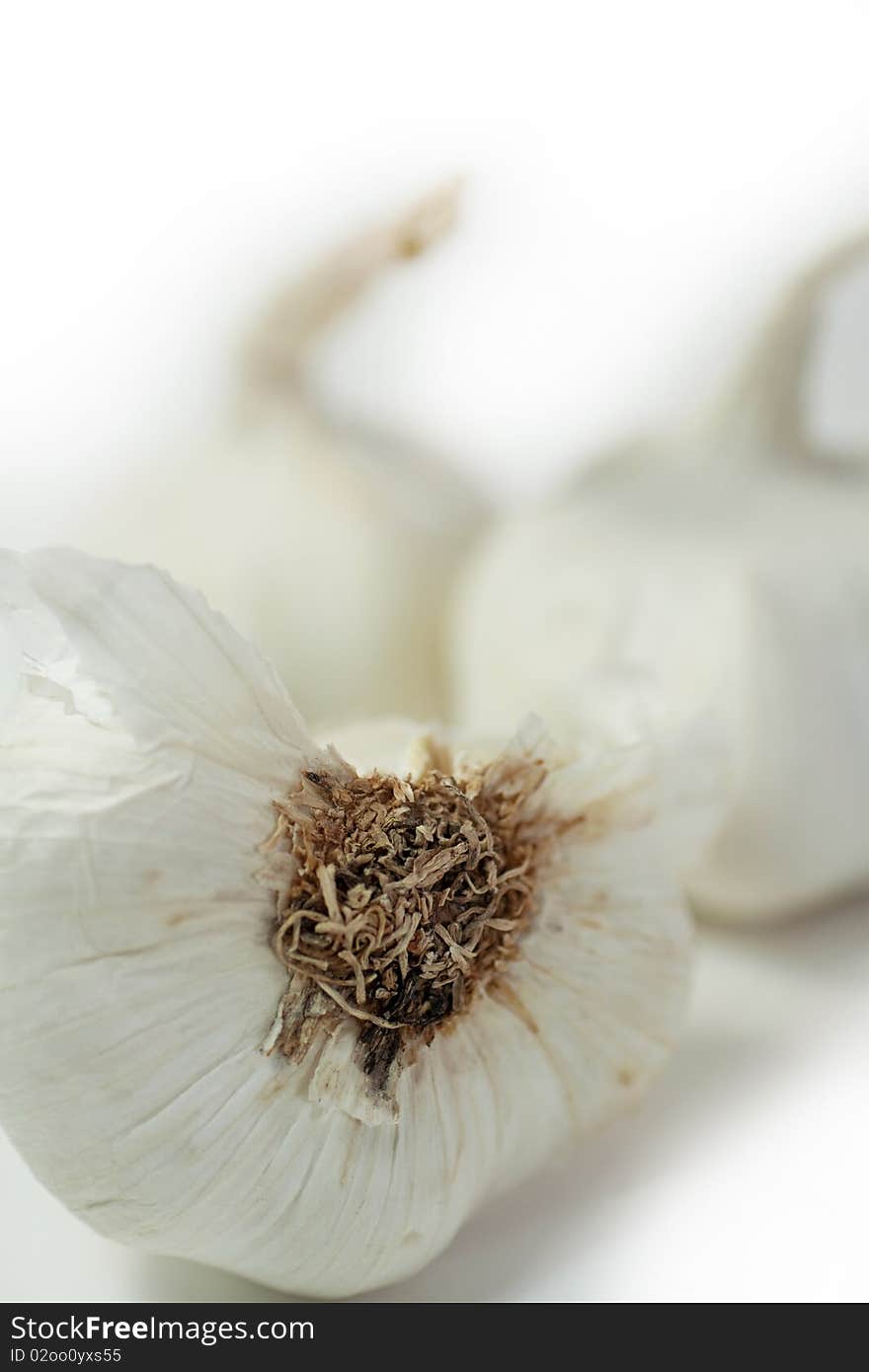 Half clove of garlic on white with whole cloves blurred in the background