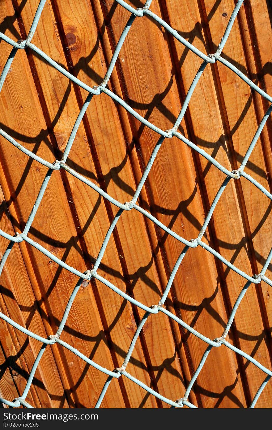 Texture background of the pine boards and metal lattice on sunlight. Texture background of the pine boards and metal lattice on sunlight.