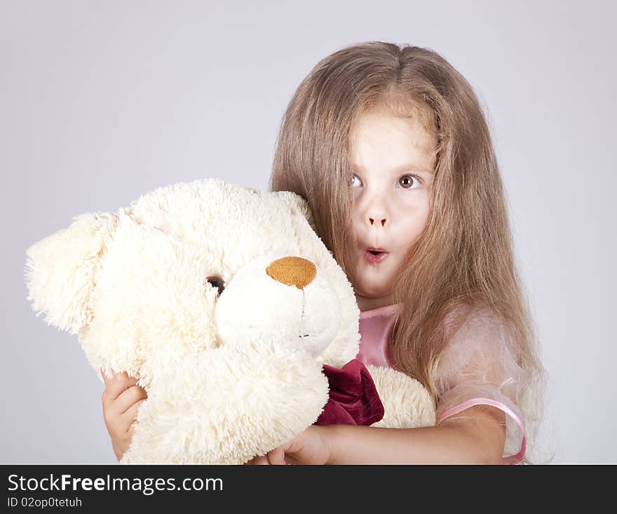 Little shouting girl embraces bear cub. Studio shot.