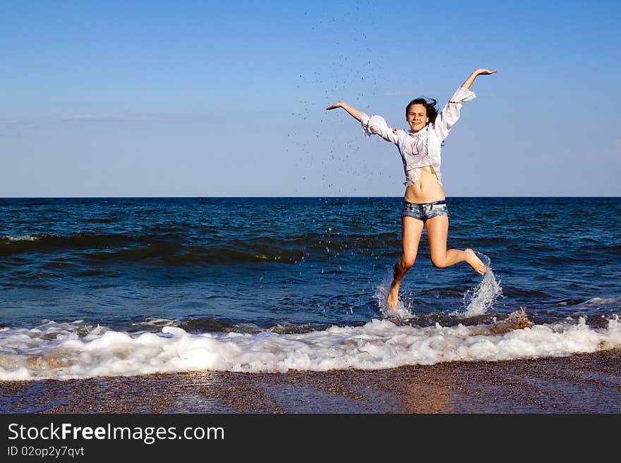 Happy girl in shorts and a white shirt on the sea. Happy girl in shorts and a white shirt on the sea