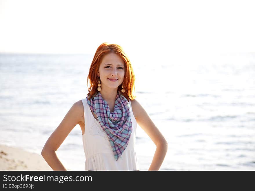 Beautiful red-haired girl at sunrise on the beach. Outdoor photo.