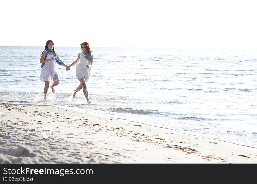 Two beautiful girls running on the beach. Outdoor photo.