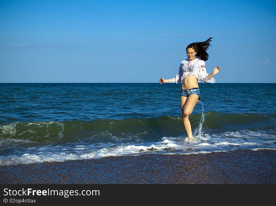 Happy girl in shorts and a white shirt on the sea. Happy girl in shorts and a white shirt on the sea