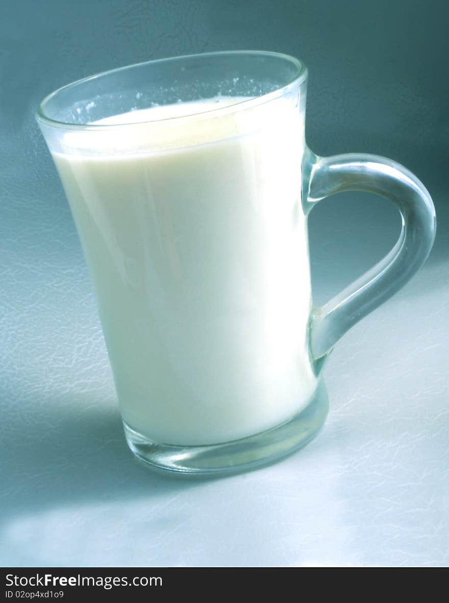 Milk in clear glass beaker on a sloping, white fresh milk to blue-gray background. Milk in clear glass beaker on a sloping, white fresh milk to blue-gray background