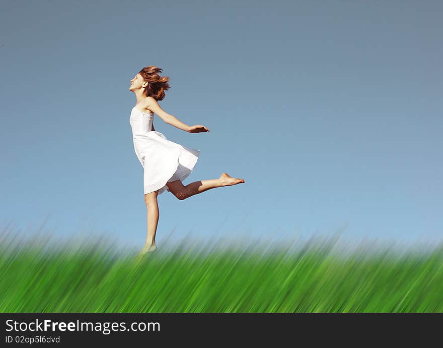 Young woman in white dress running on meadow with blurred grass