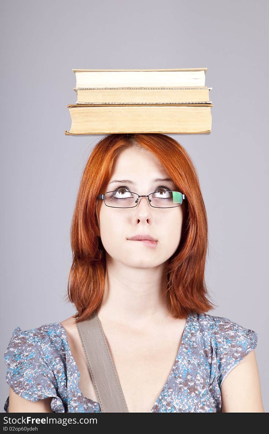 Red-haired girl keep books on her head.