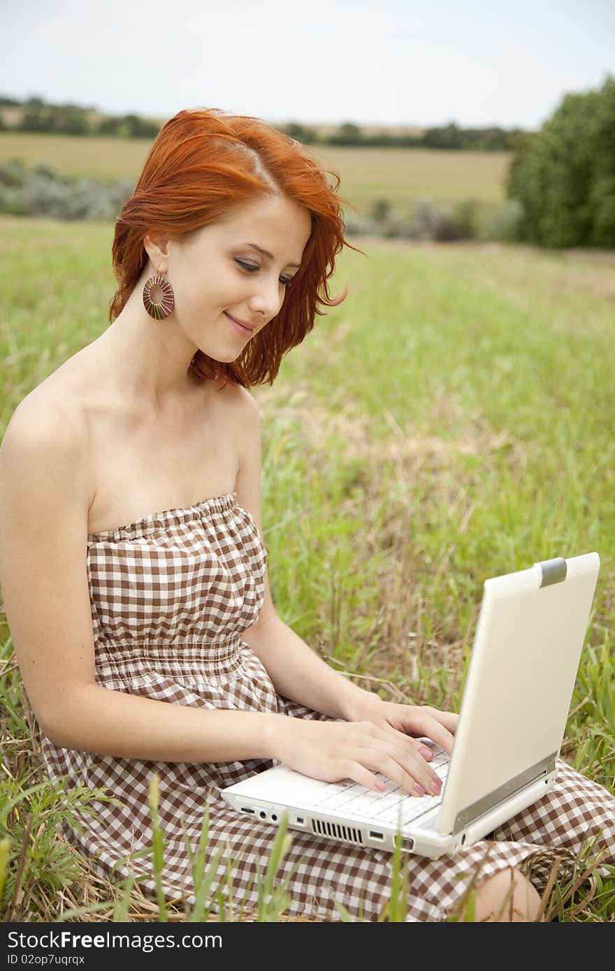 Young  fashion girl with noteboot at field. Outdoor shot.