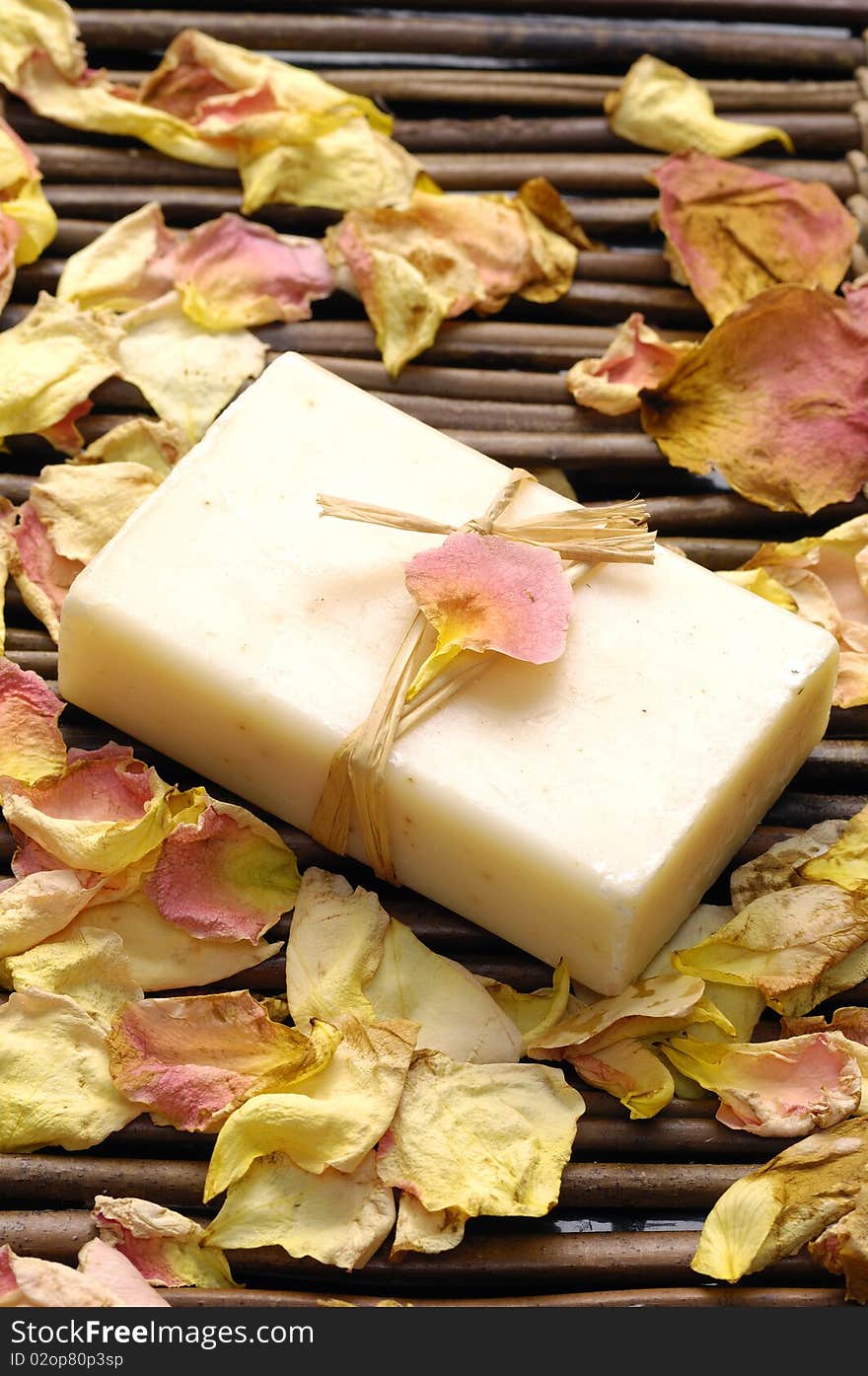 Natural soap and red candle with petals on mat. Natural soap and red candle with petals on mat