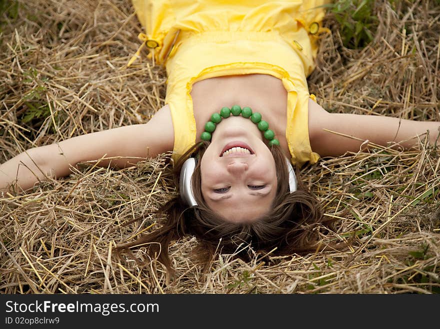 Young beautiful girl in yellow with headphones at field.