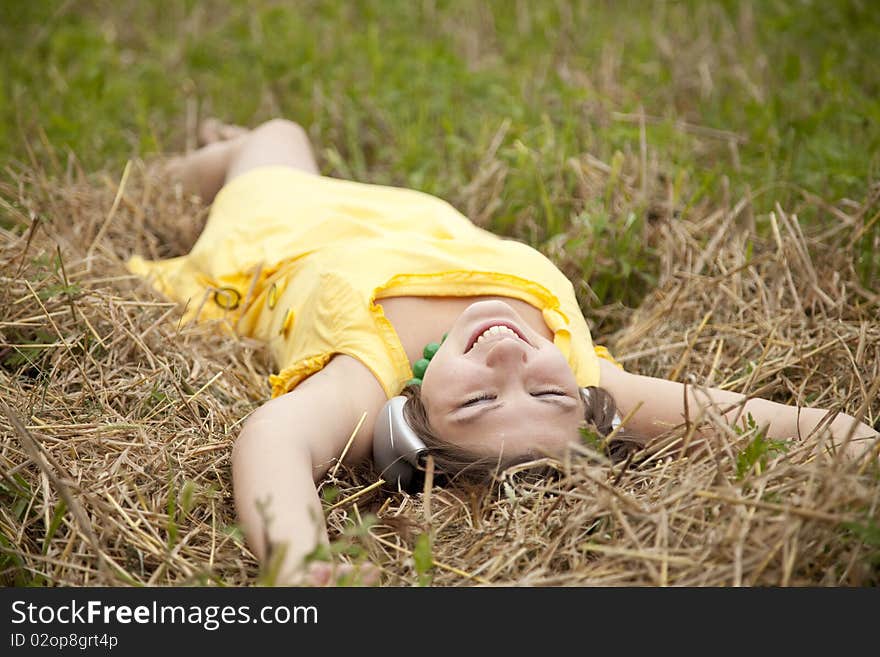 Young beautiful girl in yellow with headphones at field.