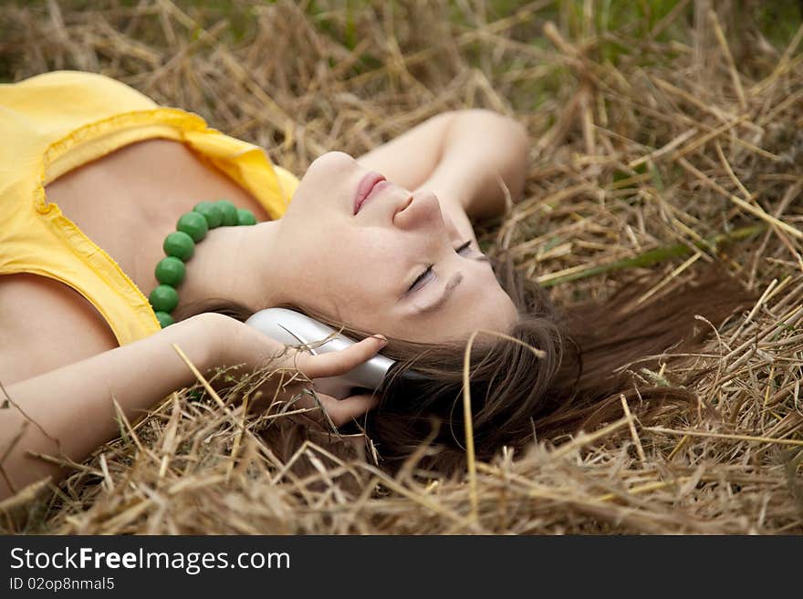 Young beautiful girl in yellow with headphones at field.