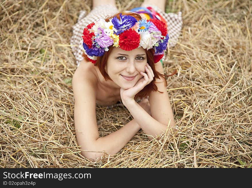 Girl in Slav national wreath lying at field. Outdoor shot.