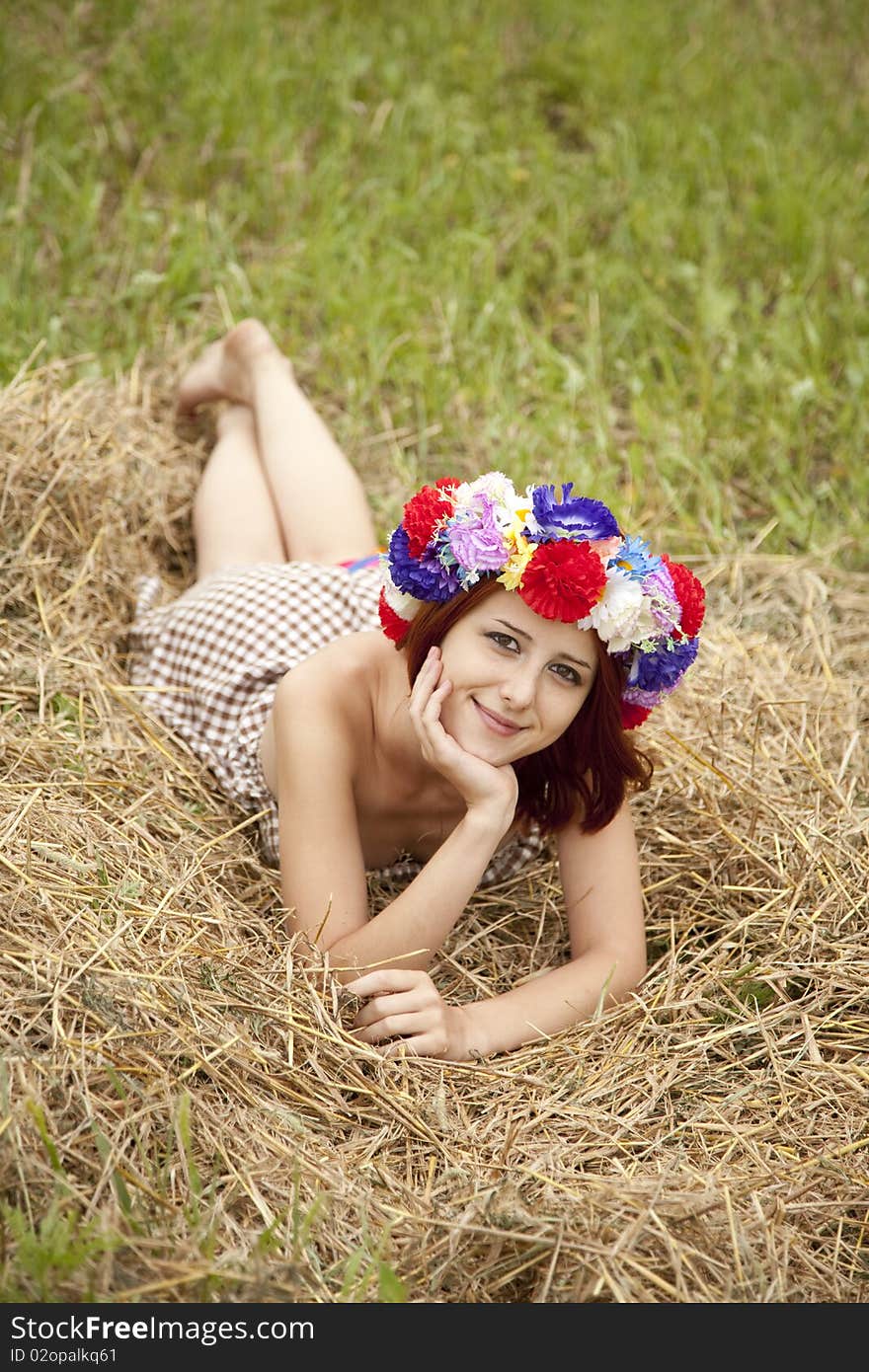 Girl in Slav national wreath lying at field. Outdoor shot.