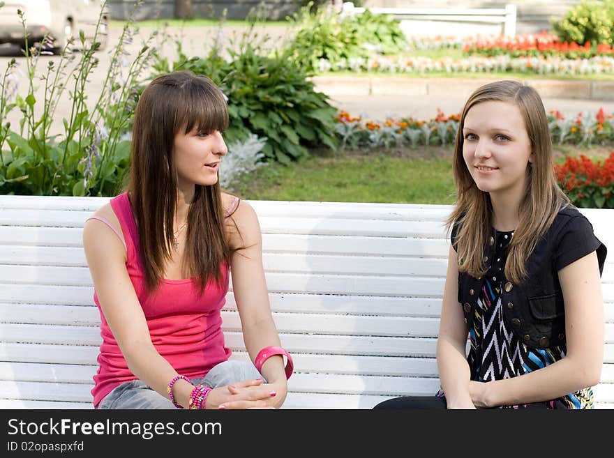 Two female friends sitting on bench