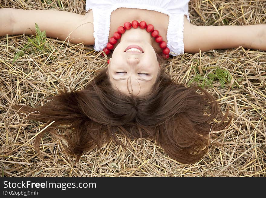 Beautiful girl lying at hay field.