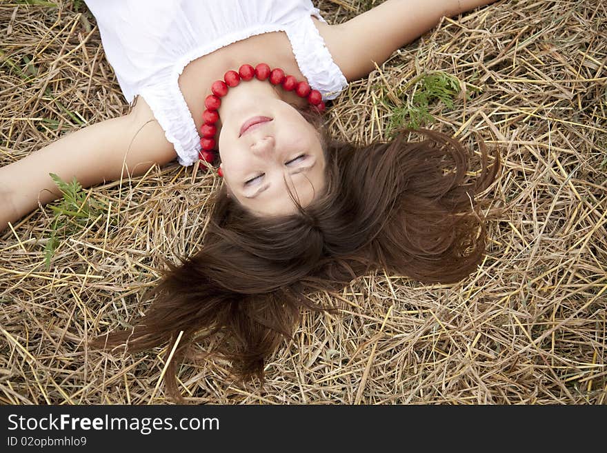 Beautiful girl lying at hay field.