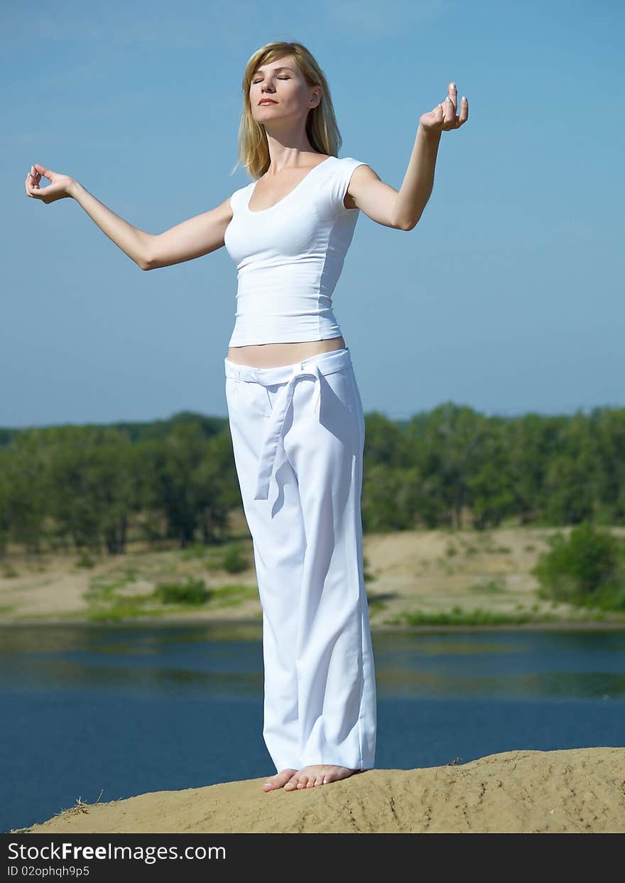 The girl in meditation on a background of the dark blue sky in the summer. The girl in meditation on a background of the dark blue sky in the summer