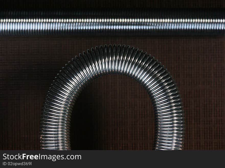 Metal spring deformed on an arch on a brown background.