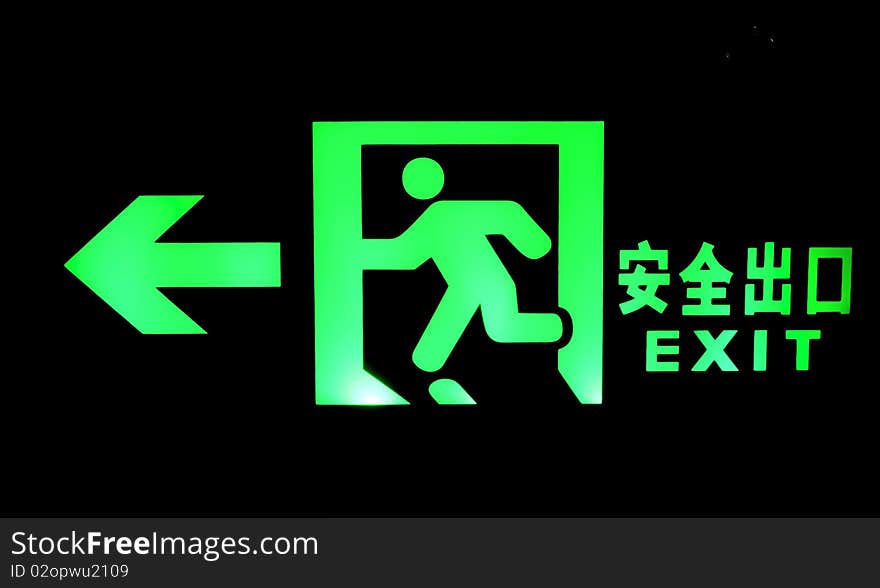 Emergency exit sign shine bright green light in darkness.