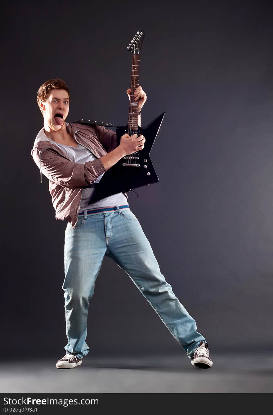 Picture of a passionate guitarist playing an electric guitar and sticking the tongue out