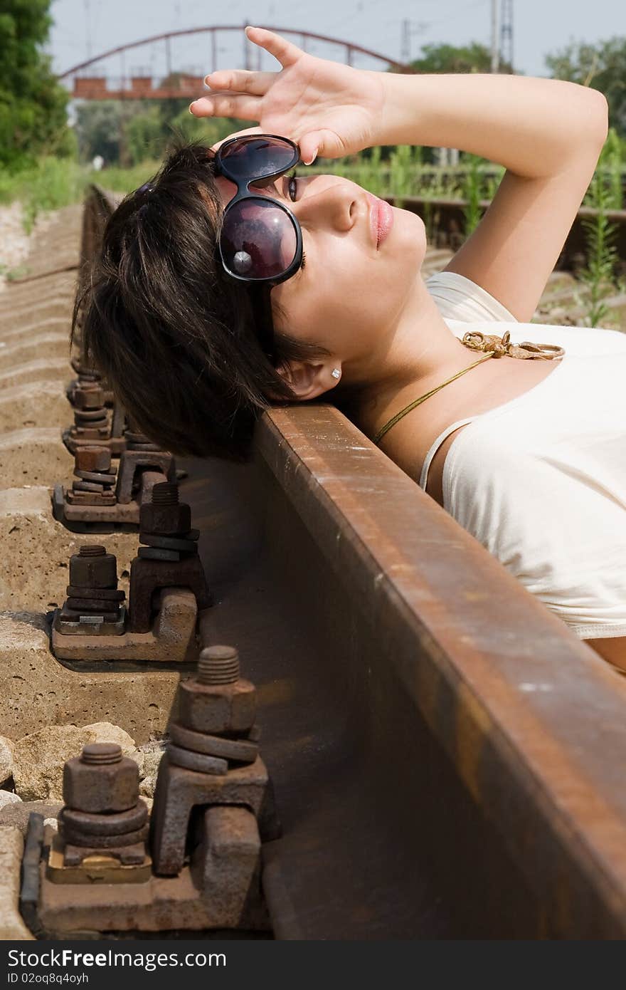 Young brunette girl laying on the railroad at day. Young brunette girl laying on the railroad at day