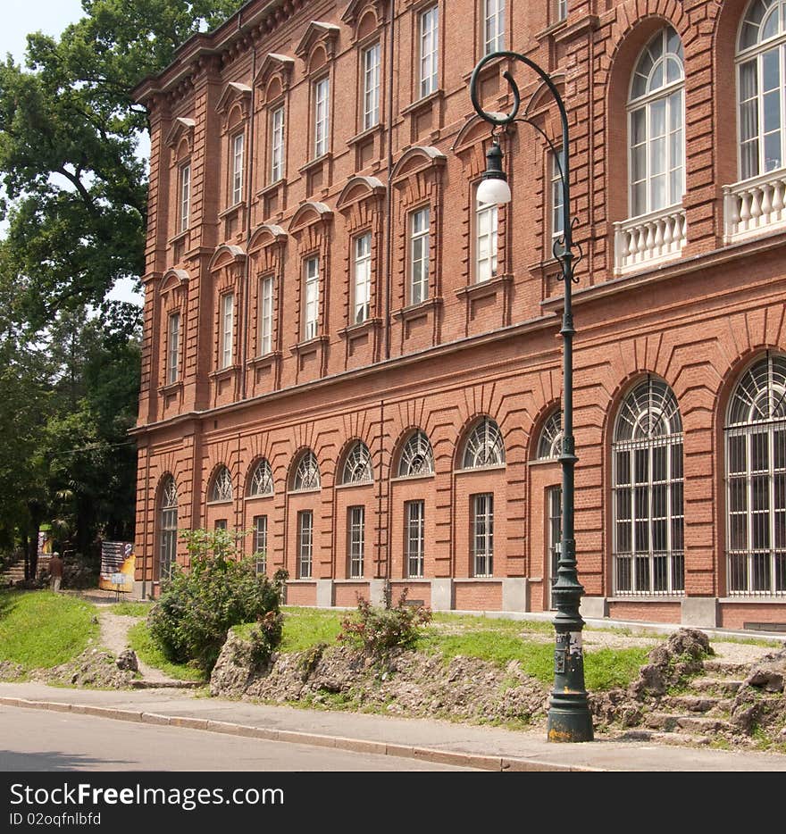 University building in Torino, Italy, with park and old-fashioned lamppost in the foreground. University building in Torino, Italy, with park and old-fashioned lamppost in the foreground