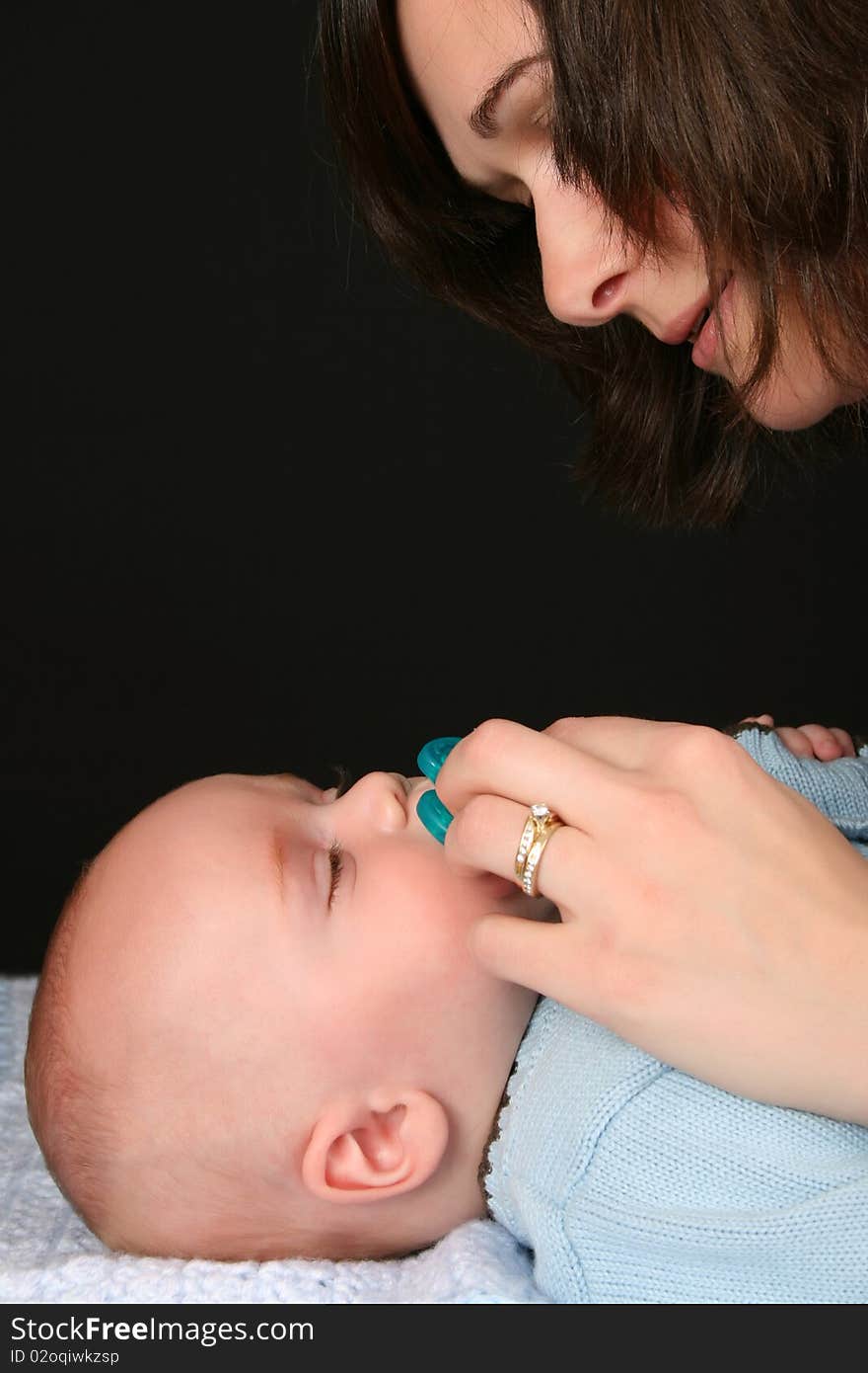 Brunette mother consoling her baby with a dummy. Brunette mother consoling her baby with a dummy