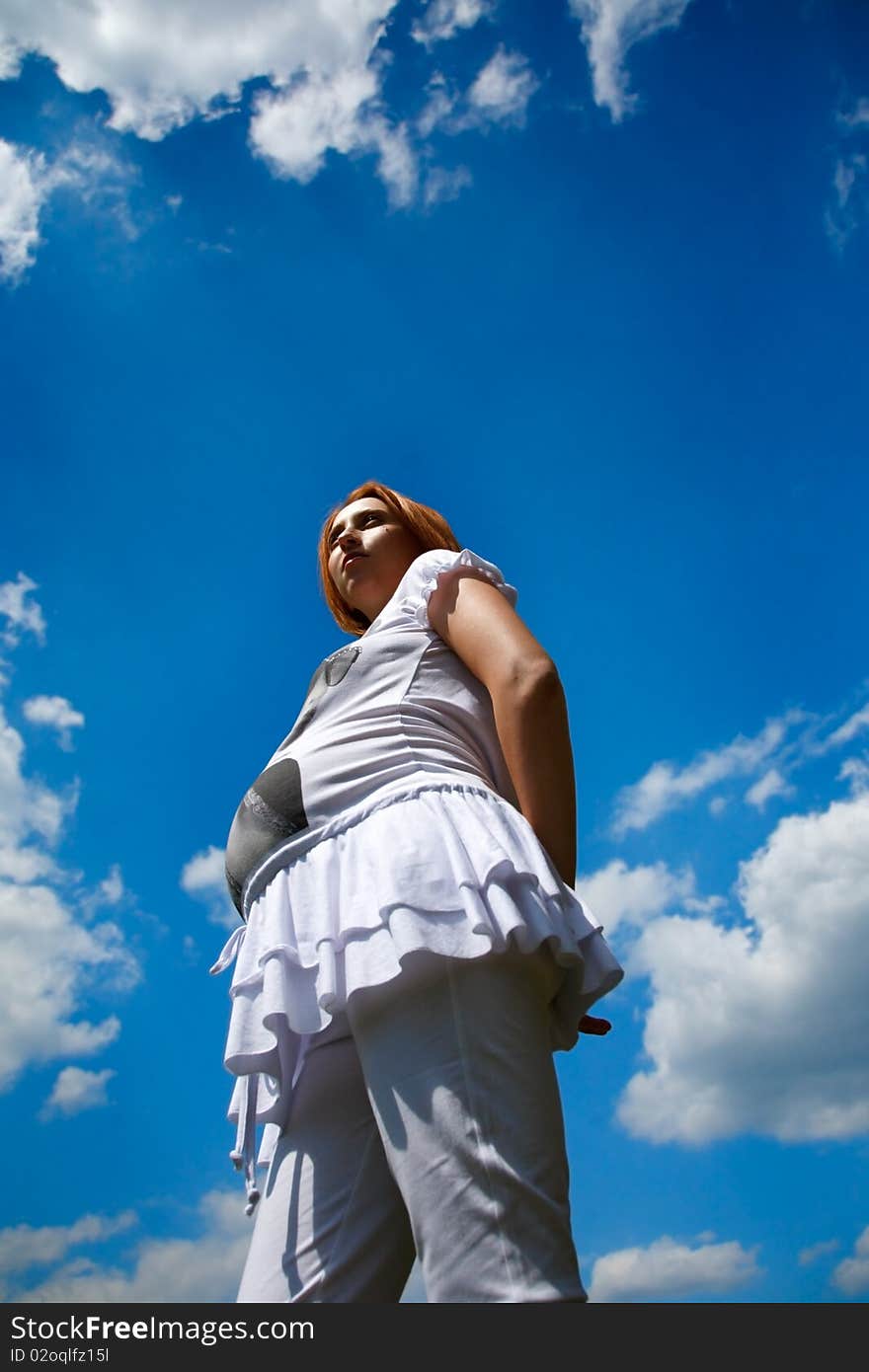 Pregnant woman on cloudy blue sky background