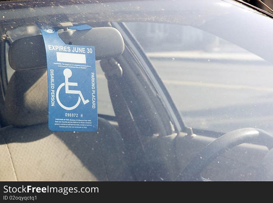 Handicap sign on a rear view mirror, in a muddy car.