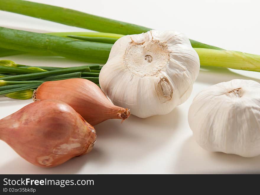 Mixed vegetables of onions, garlic, green onions, and herbs in a white background