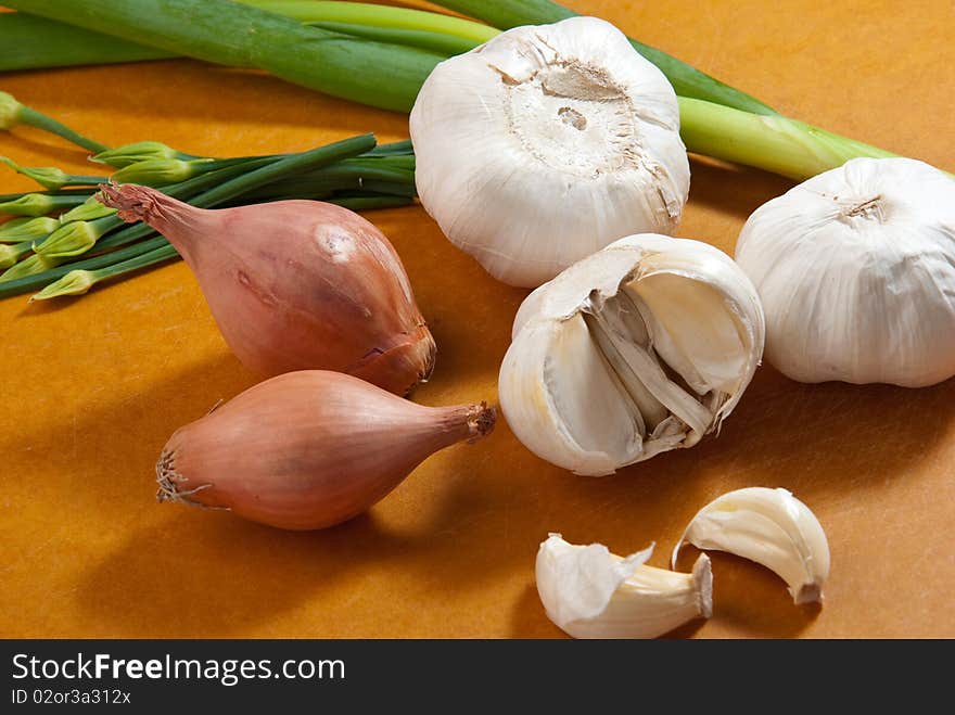 Mixed vegetables of onions, garlic, green onions on cutting board.