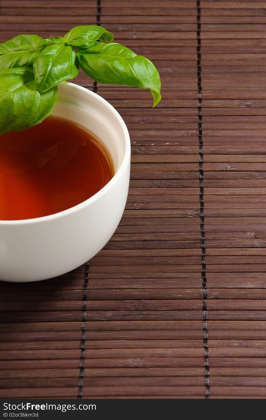 Cup of tea with basil leaves on a bamboo mat. Cup of tea with basil leaves on a bamboo mat