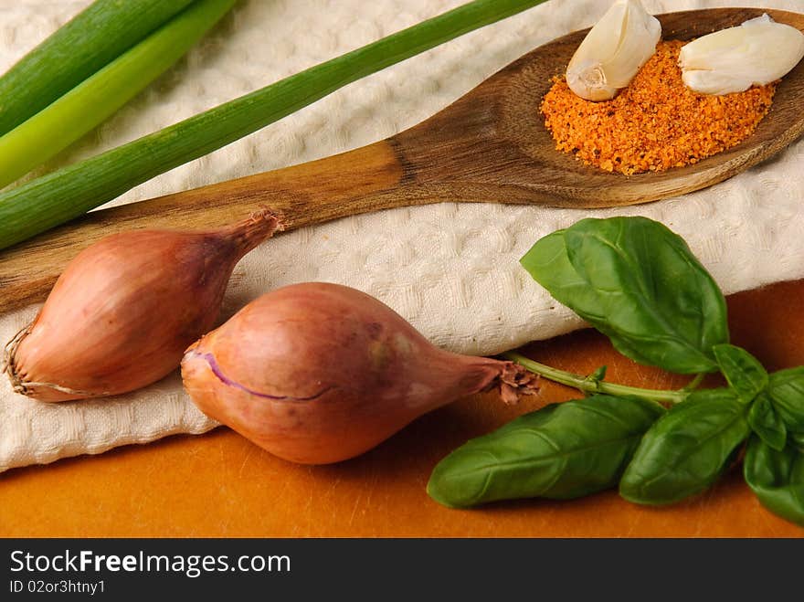 Spices on wooden spoon with green onions and basil leaves on a towel. Spices on wooden spoon with green onions and basil leaves on a towel