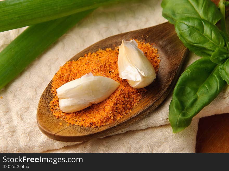 Spices on wooden spoon with basil leaves on a tea towel. Spices on wooden spoon with basil leaves on a tea towel