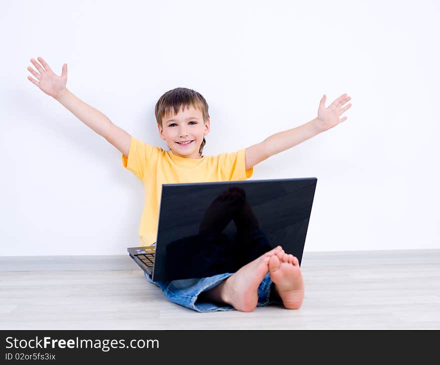 Happy little boy with laptop with moving apart his hands - indoors. Happy little boy with laptop with moving apart his hands - indoors