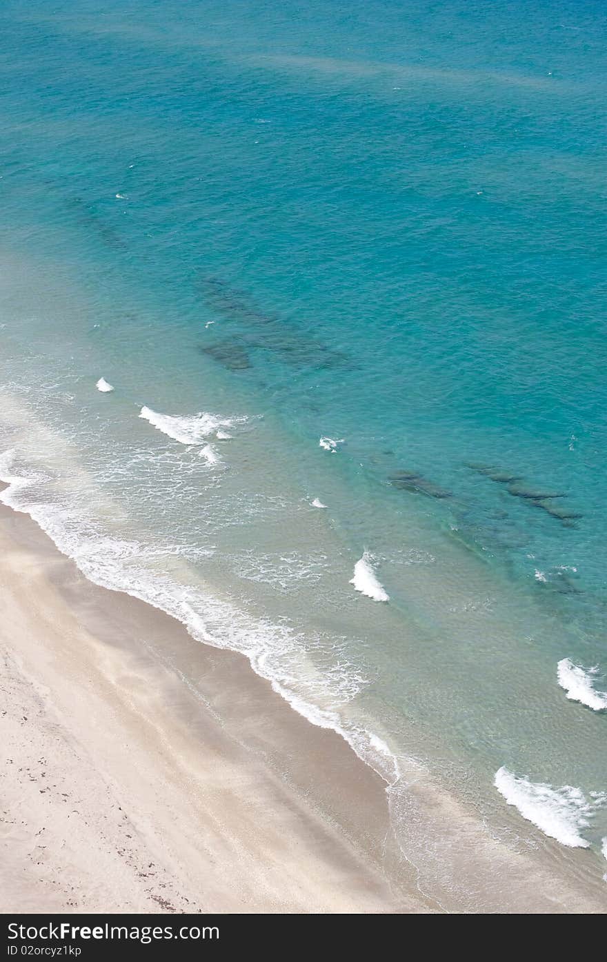 Panoramic from above of beach and ocean. The waves are coming to the beach and the ocean is tranquil