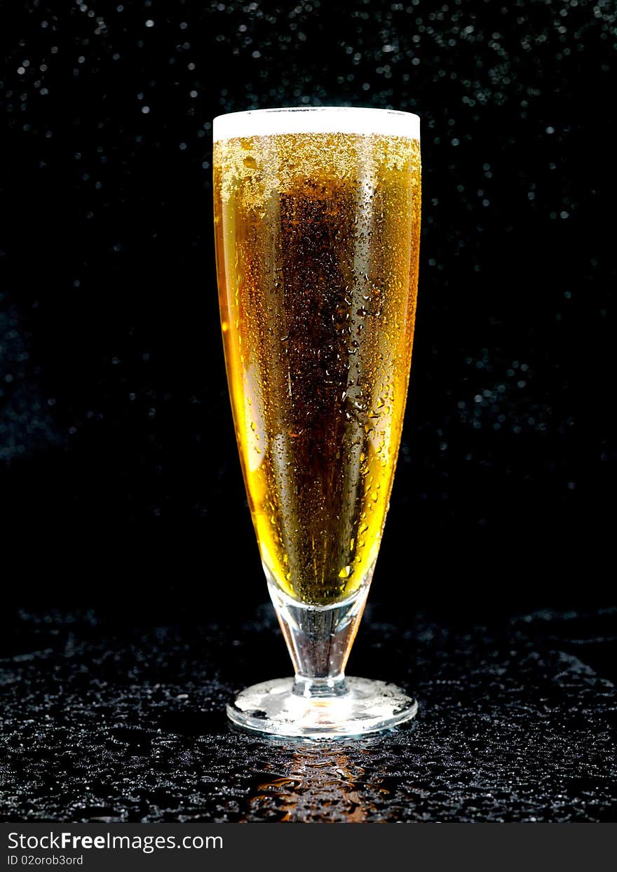 A glass of beer isolated against a black background. A glass of beer isolated against a black background