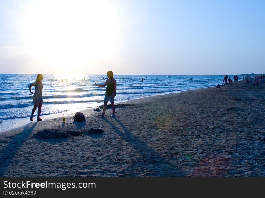 Beautiful sunset on the sea with the silhouettes of people walking on the beach