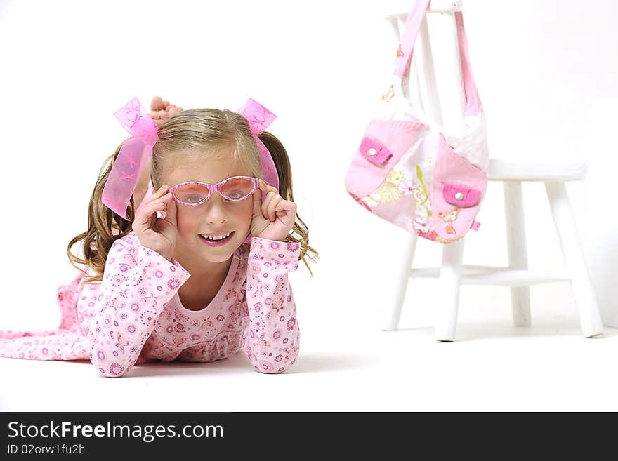 Young pretty blond girl with sunglasses, laying on the floor next to a white chair and pink hand bag. Young pretty blond girl with sunglasses, laying on the floor next to a white chair and pink hand bag