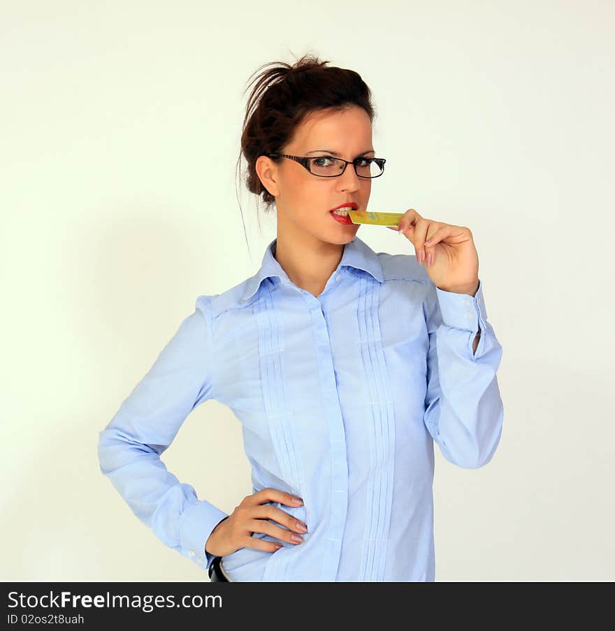 Girl wearing eyeglasses is holding credit card in her mouth. Girl wearing eyeglasses is holding credit card in her mouth